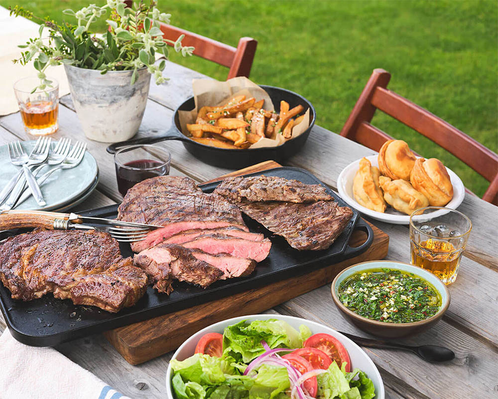 grilled meat with sides on a summer outdoor picnic table