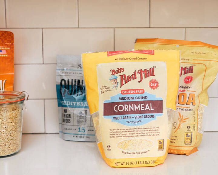 Packages of cornmeal and quinoa on a pantry shelf.