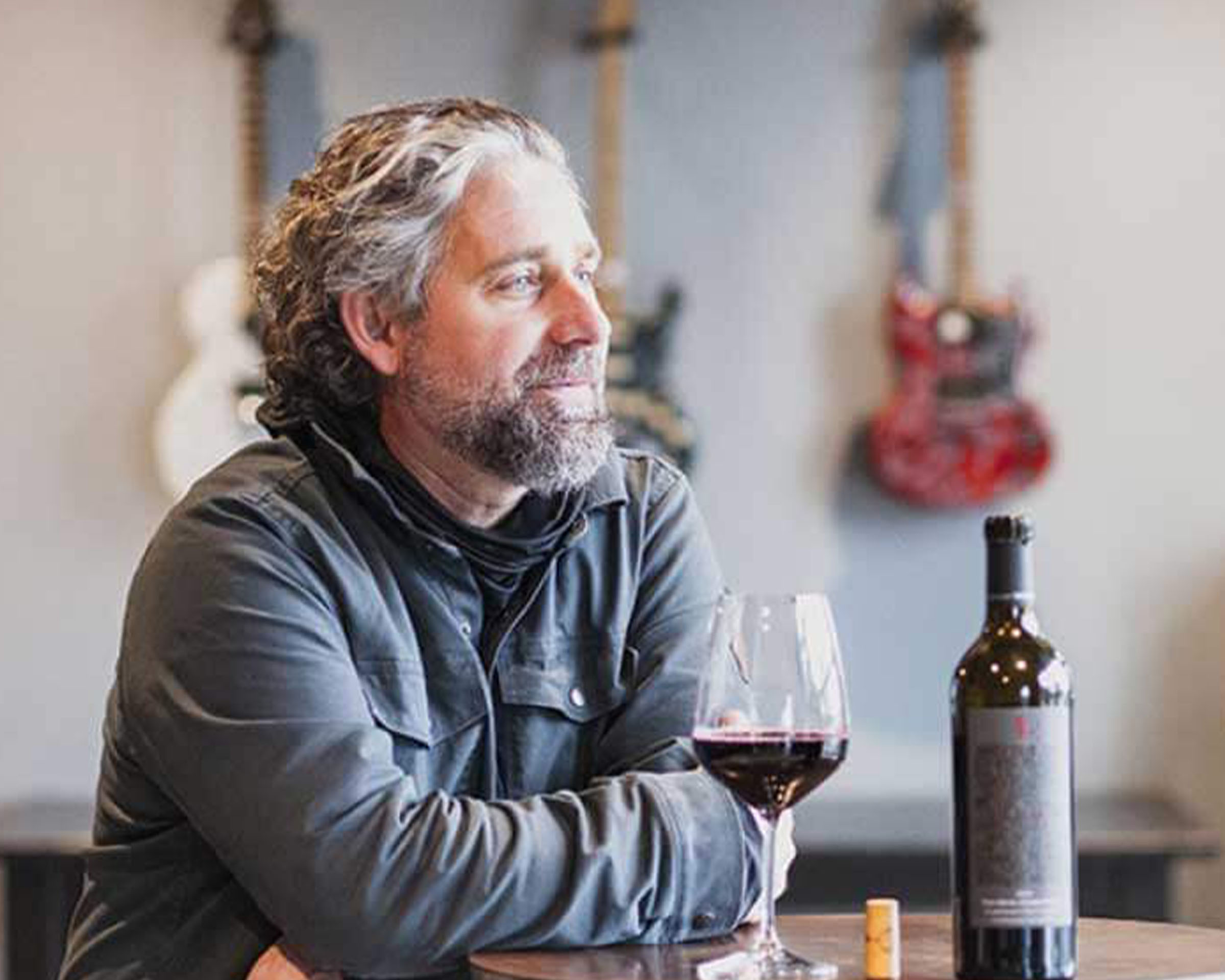 Chris Gorman leaning on a table with a glass of wine