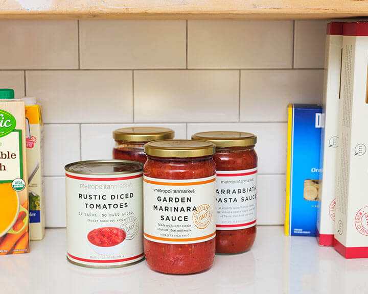 Cans of tomato products on a pantry shelf.