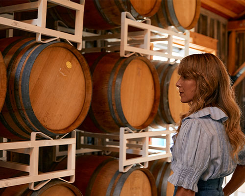 Audra Lawlor standing in front of barrels of wine.