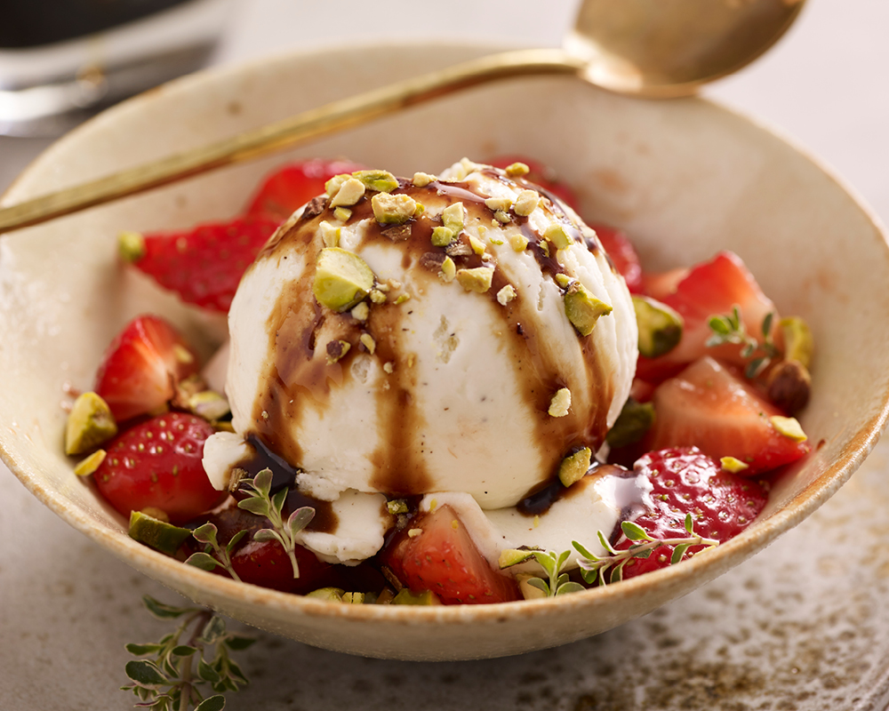 Balsamic vinegar drizzled over ice cream with pistachios and strawberries